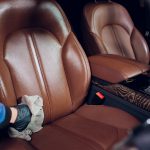 Auto service staff cleaning car interior - car detailing and valeting concept