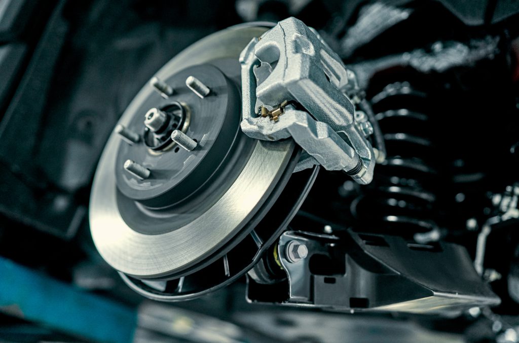 Disc brake of the vehicle for repair, in process of new tire replacement. Car brake repairing in garage.Suspension of car for maintenance brakes and shock absorber systems.Close up.
